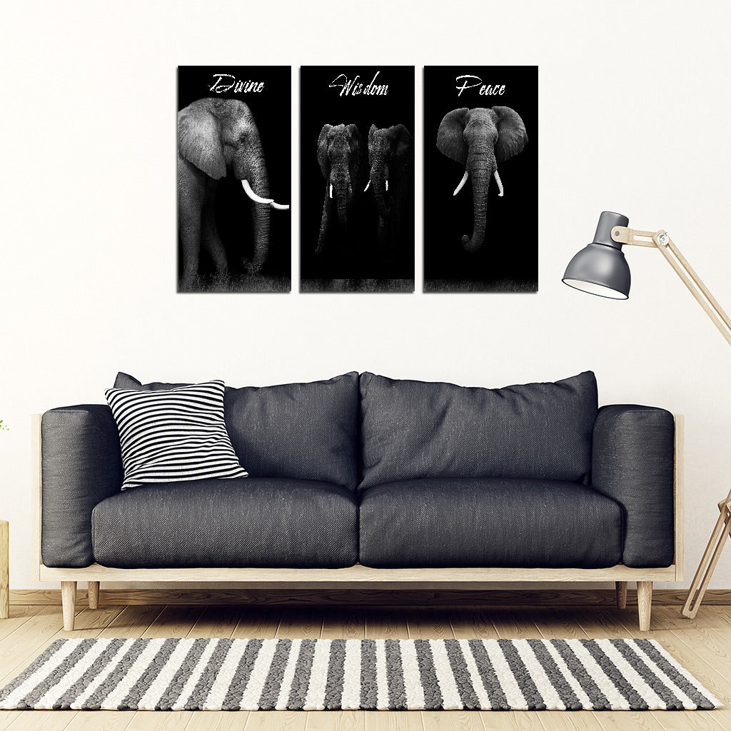 A framed canvas artwork featuring three different side-by-side images of an elephant, with the word 'ELEPHANT' written at the top of each canvas. The artwork is displayed above a gray sofa with a lamp and a striped throw pillow to the side, set against a white wall.